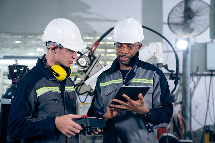 Two Men Manufacturing Workers in hardhats holding tablets